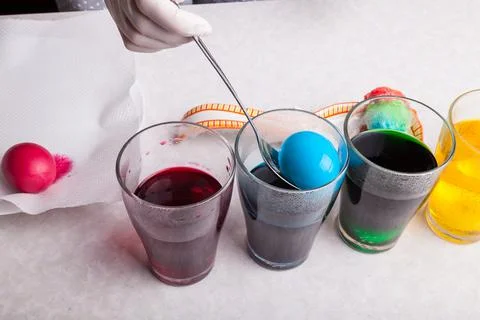 The process of dyeing Easter eggs at home close-up of female hands in latex g Stock Photos