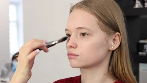 The process of face makeup brush alignment of the face tone on a beautiful young Stock Footage 148658345