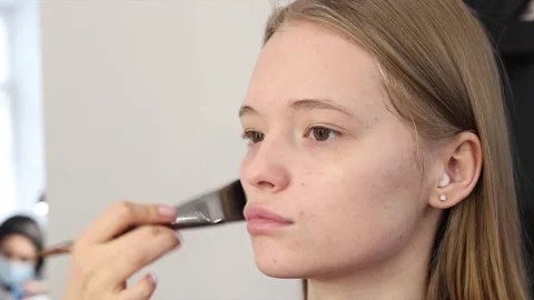 The process of face makeup brush alignment of the face tone on a beautiful young Stock Footage 148679215
