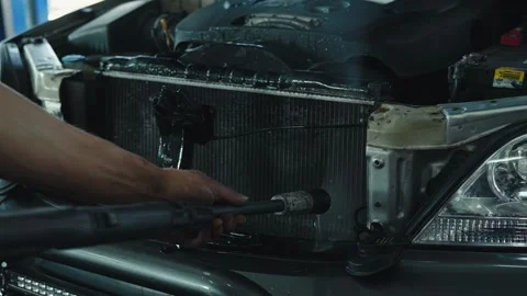 The process of flushing a car cooling radiator under high pressure at a service Stock Footage 284545602