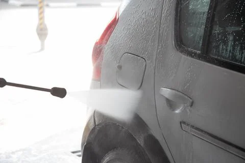 A process of flushing soap sud on silver car with pressurised water stream at Photos