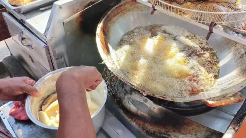 The process of frying bananas by placing batter-dipped bananas into a wok w.. Stock Footage 330460073