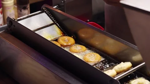 The process of frying donuts in an automatic deep fryer with oil 動画素材 343681711