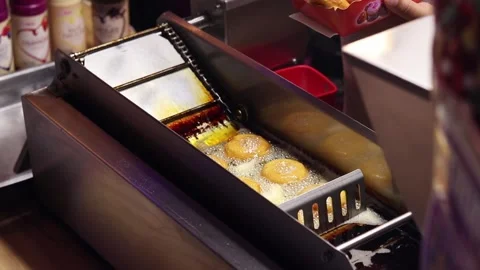 The process of frying donuts in an automatic deep fryer with oil Stock-Footage 343681718