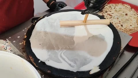 Process of frying pancakes. Cook rolls dough in hot pan. Spreading batter on Stock Footage 317947581