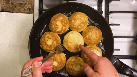 The process of frying syrniki in vegetable oil in a frying pan on the stove.	 Stock Footage 301328342