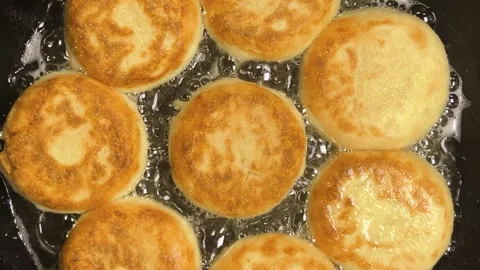 The process of frying syrniki in vegetable oil in a frying pan on the stove.  Stock Footage 301883620