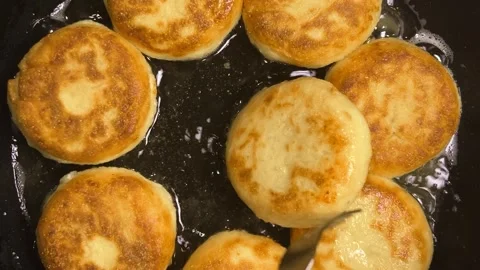 The process of frying syrniki in vegetable oil in a frying pan on the stove.  Stock Footage 301884279