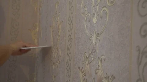 The process of gluing Wallpaper on the wall,the hand of the worker to smooth the Stock Footage 79597047