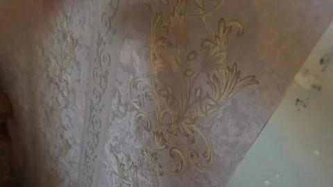 The process of gluing Wallpaper on the wall,the hand of the worker to smooth the Stock Footage 79597499