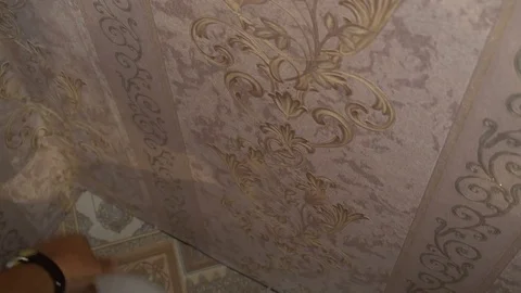 The process of gluing Wallpaper on the wall,the hand of the worker to smooth the Stock-Footage 79597845