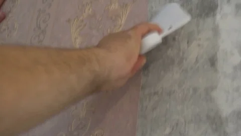 The process of gluing Wallpaper on the wall,the hand of the worker is smooth Stock Footage 79598716