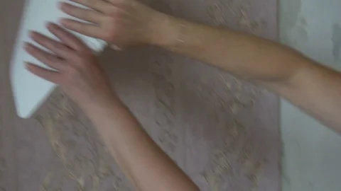 The process of gluing Wallpaper on the wall,the hand of the worker to smooth the Stock Footage 79599833