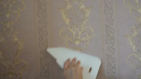 The process of gluing Wallpaper on the wall,the hand of the worker to smooth  Stock Photos