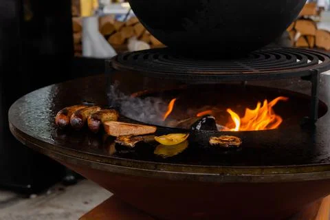 Process of grilling sausages, toast bread slice, pepper on round brazier Stock Photos