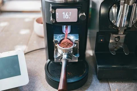 Process of grinding coffee beans pouring into a portafilter using coffee machine Foto stock