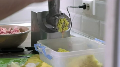 Process of grinding potato in the kitchen through electric grinder. Cooking at Stock Footage 165068395