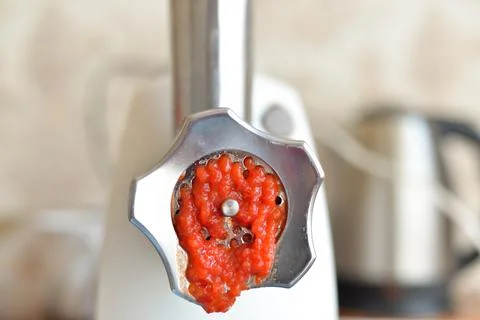 The process of grinding red tomatoes in a meat grinder Stock Photos