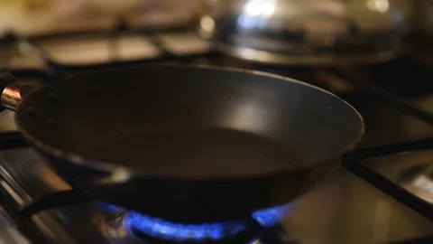 Process of heating frying pan on gas stove. Hand pours oil into a hot pan Stock Footage 119359732