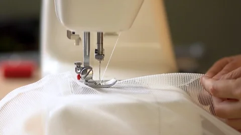 The process of hemming the edges of curtains from white mesh fabric on a sewing Stock-Footage 126652623