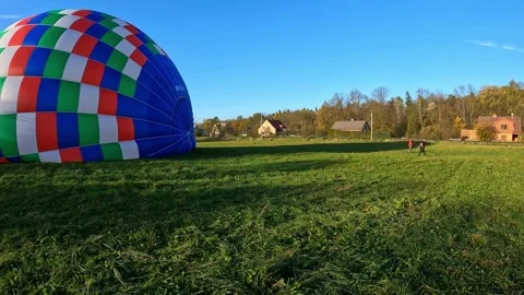 Process of hot air balloon preparation and launch in a green field on a sunny da Stock Footage 242184487