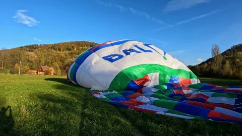 Process of hot air balloon preparation and launch in a green field on a sunny da Stock Footage 242185534