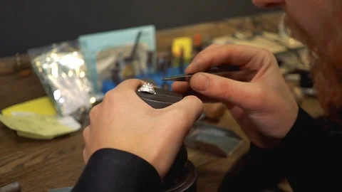 Process of inserts gems into a silver ring using tweezers by jeweler Stock Footage 73528567
