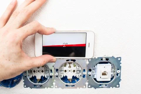 The process of installation electrical sockets level with a smartphone Stock Photos