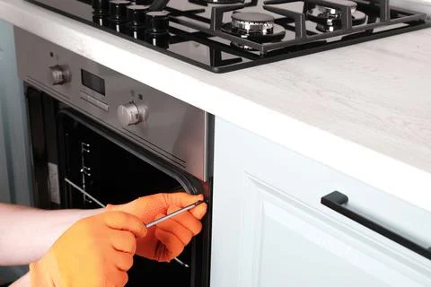 Process of installing an electric oven in  kitchen,  hands of  serviceman Foto stock
