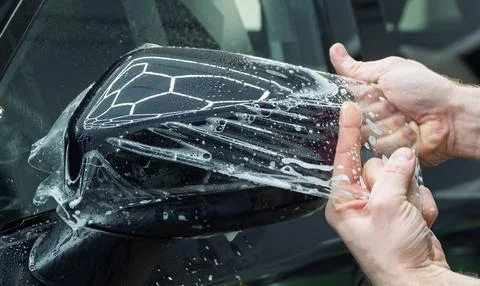 The process of installing PPF on the side of the car. Stock Photos