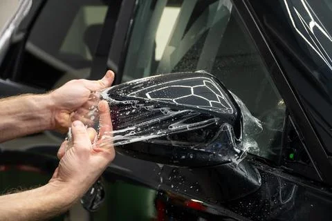 The process of installing PPF on the side mirror the car. Stock Photos