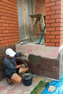 The process of installing sandstone decorative tiles on the foundation of the Foto stock