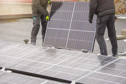 The process of installing solar panels. Solar panel installers work on the roof Stock Photos