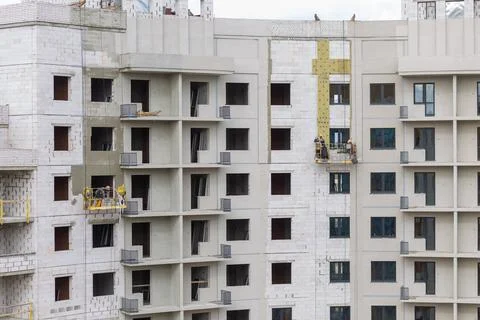 The process of insulating external walls in a multi-storey building under con Фото