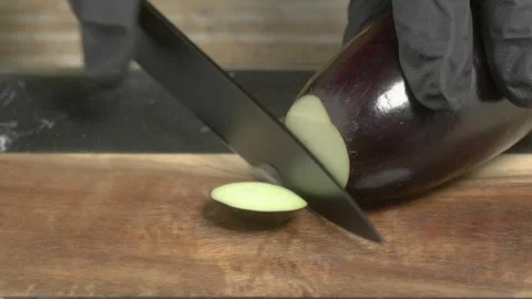 The process involves slicing eggplant on a wooden chopping board in the kitchen Video stock 280253648