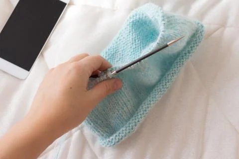 The process of knitting the blue caps from threads on the background of the p Stock Photos