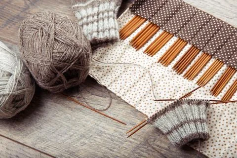 The process of knitting sock with circular bamboo knitting needles, on a wooden Stock Photos