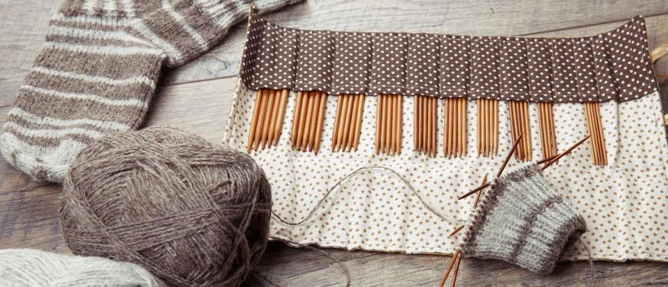 The process of knitting sock with circular bamboo knitting needles, on a wooden Stock Photos