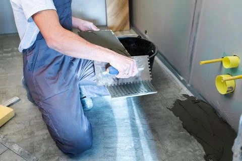 The process of laying ceramic floor tiles with a herringbone pattern. Stock Photos