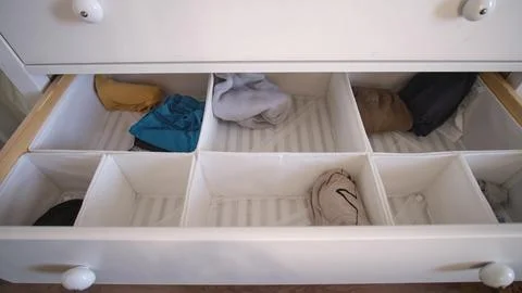 The process of laying out children's things and clothes in a chest of drawers Stock Photos