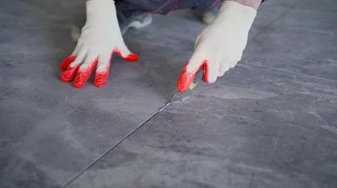 The process of laying tiles on the floor. The process of removing grout between Stock Photos