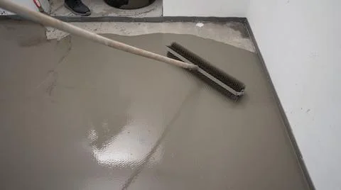 The process of leveling the self-leveling floor. Worker applying epoxy and Stock Photos