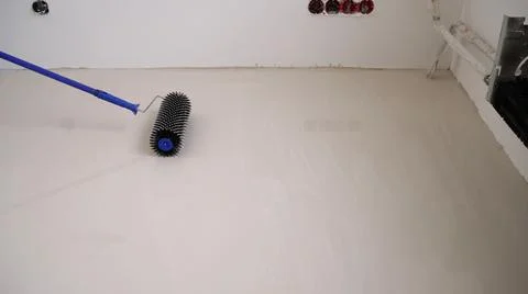 The process of leveling the self-leveling floor. Worker applying epoxy and Stock Photos