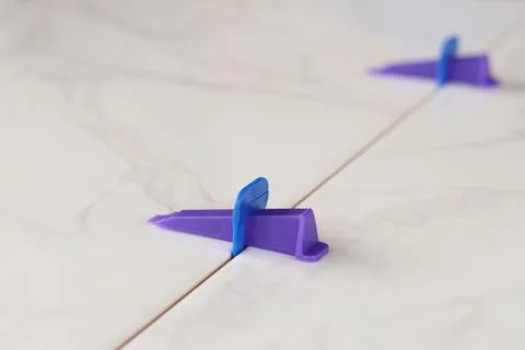 The process of leveling white marble tiles using a plastic wedge and clip Stock Photos