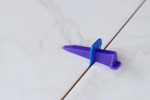 The process of leveling white marble tiles using a plastic wedge and clip Stock Photos