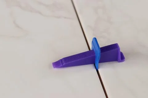 The process of leveling white marble tiles using a plastic wedge and clip Stock Photos