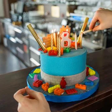 The process of lighting candles on a cake with block game theme 8th birthday. Stock Photos