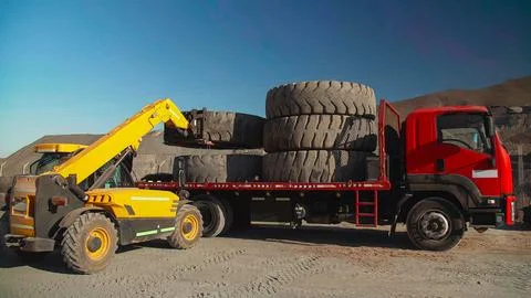 Process of loading and transporting giant tires with heavy machinery for re.. Stock Photos