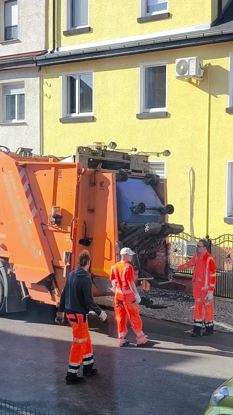 The process of loading a container into a garbage truck on a city street Stock Footage 347418391