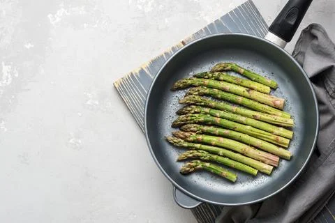 The process of making asparagus in a frying pan. Fresh asparagus in a frying  Foto stock